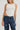 Woman wearing white cotton tank top with scoop hem and dome studs on neckline
