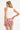 Woman wearing white cotton tank top with scoop hem and dome studs on neckline and red-and-white hawaiian print miniskirt