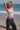 Woman wearing white cotton tank top with scoop hem and dome studs on neckline