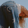 Person wearing studded blue jeans against a clear blue sky